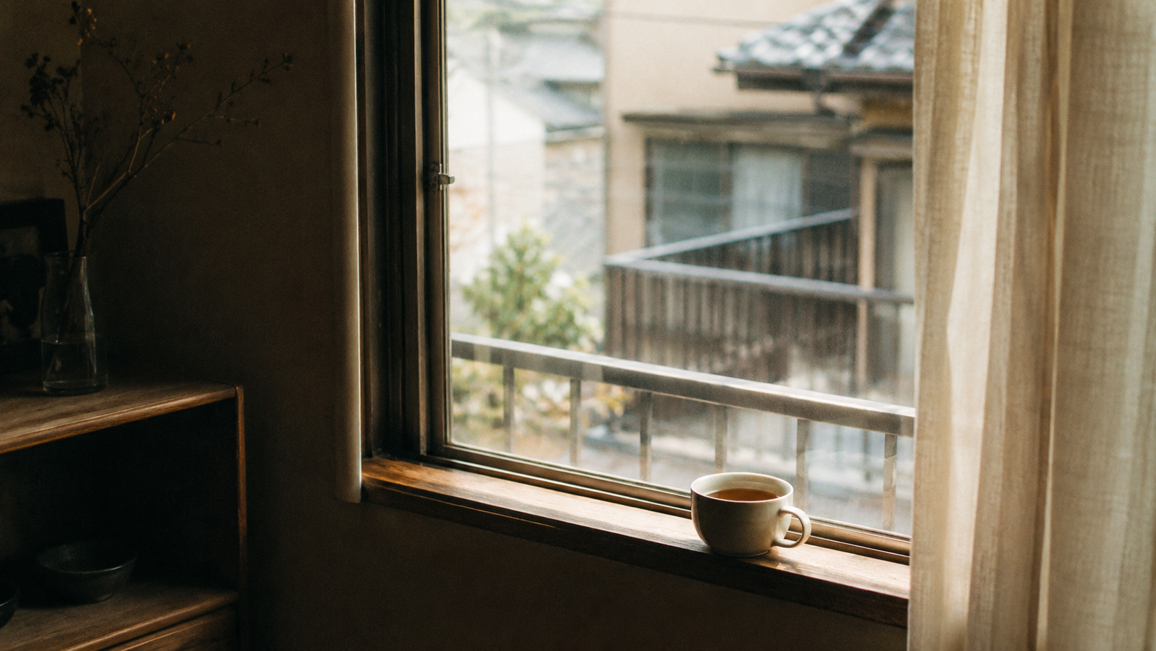 一人暮らしの部屋の窓辺に置かれた湯気の立つお茶。静かな午後の光