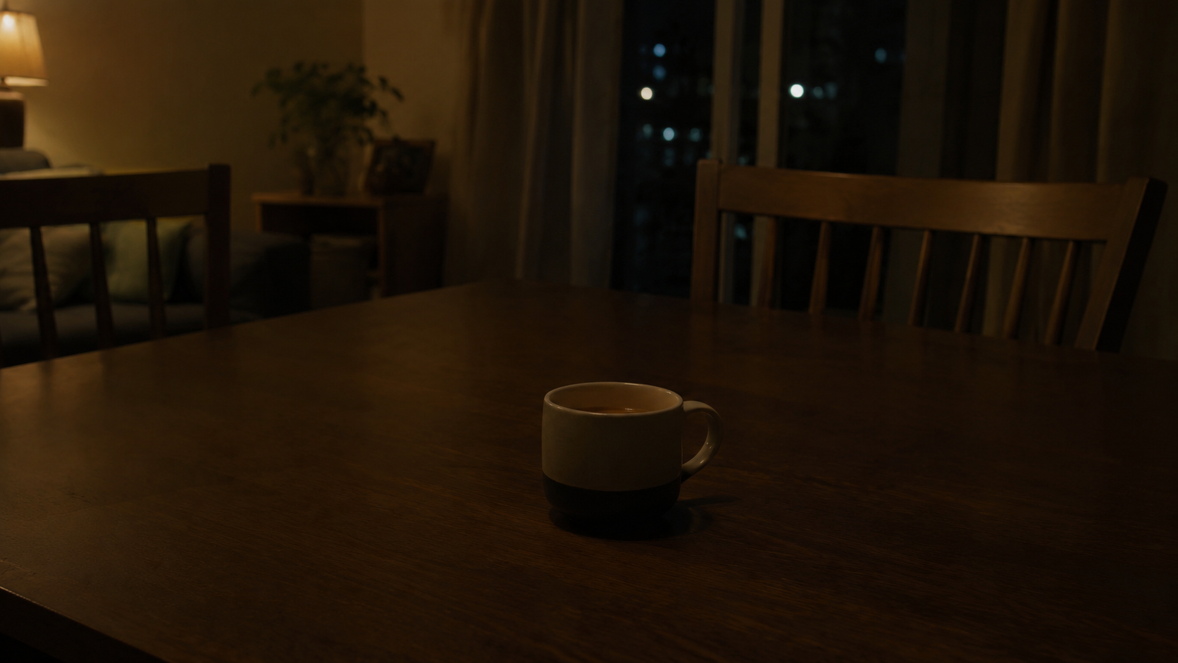 夜のテーブルに置かれた飲みかけのマグカップ。間接照明だけの薄暗い部屋