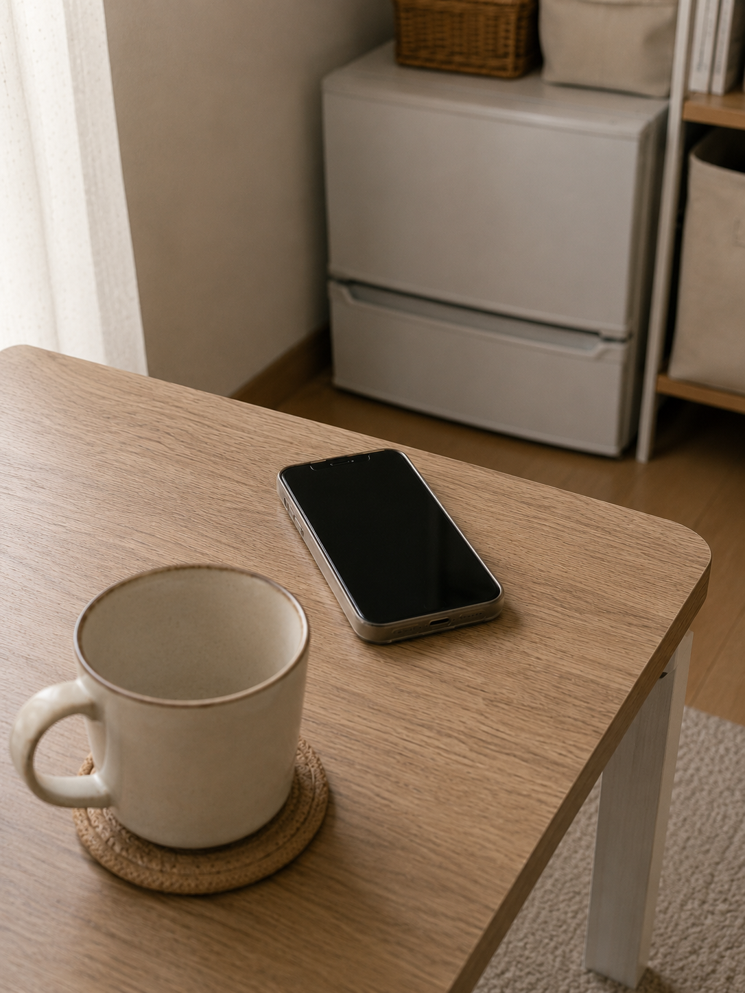 テーブルに置かれた画面の暗いスマートフォンとマグカップ