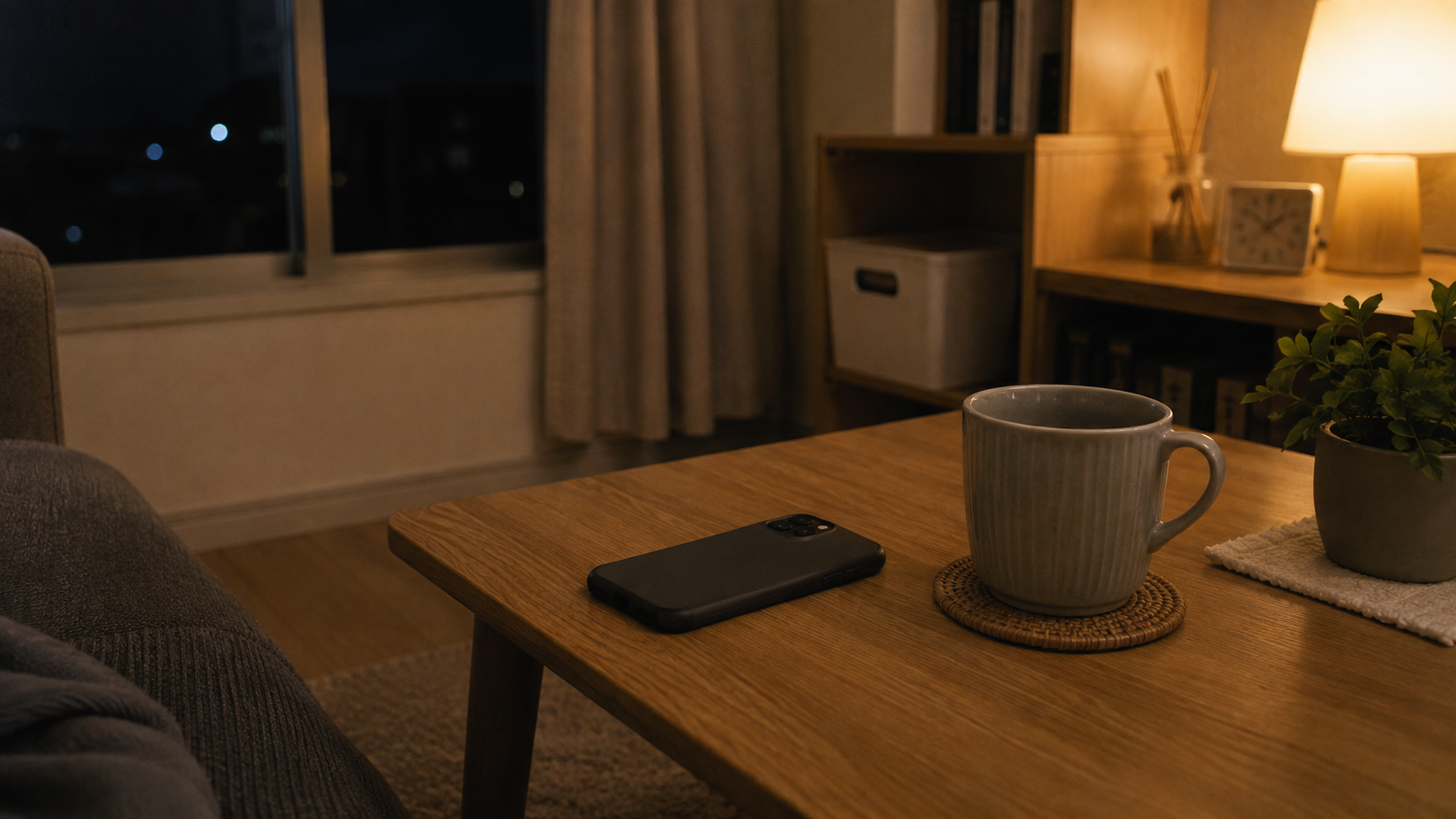 夜の部屋、テーブルに置かれたスマートフォンと静かな明かり